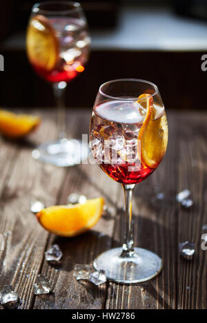 Deux cocktails rouge rafraîchissante avec orange isolé sur un fond de bois avec des oranges et de la glace avec rétroéclairage Banque D'Images