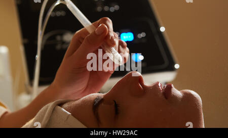 Visage soin de beauté. Gros plan du belle femme l'émission de l'eau Oxygène gaz-liquide à l'aide de l'équipement professionnel Peeling épidermique au centre de cosmétologie. Concept de soins de la peau. Banque D'Images