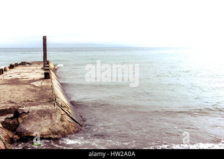 Béton vieux jetty pier besoin de réparation dépasse dans une mer calme avec plus de vigueur apparente. Banque D'Images