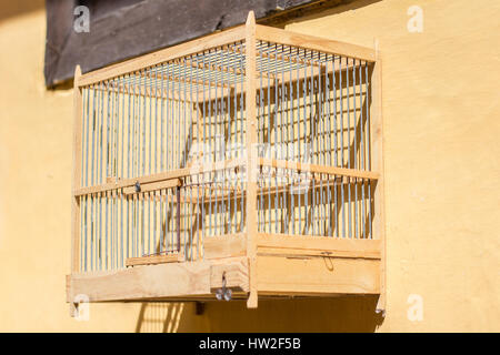 Cage à oiseaux en bois vide accroché sur mur jaune Banque D'Images