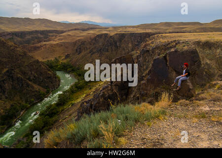 Caucasian woman sitting on mountain rocks photographier river Banque D'Images