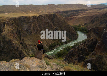 Caucasian woman sitting on mountain rocks photographier river Banque D'Images