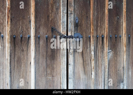 Porte en bois verrouillée de la chaîne avec de grands clous de fer et ornements métalliques Banque D'Images