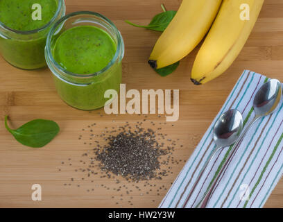 Épinards vert, semences chia, banane et de protéines en poudre dans deux bocaux smoothie sur la surface en bois de bambou. petit-déjeuner sain, snack-. detox, végétalien, vegetar Banque D'Images