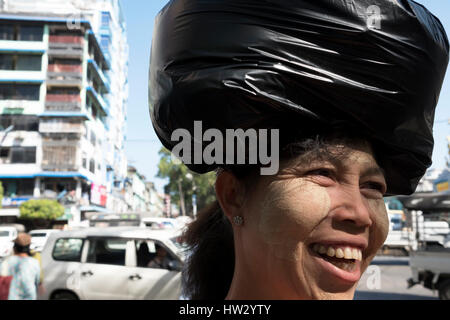 Une femme birmane à visage crème, porte un sac plastique sur sa tête dans la pagode Sule, Yangon, Yangon, Myanmar Région Banque D'Images