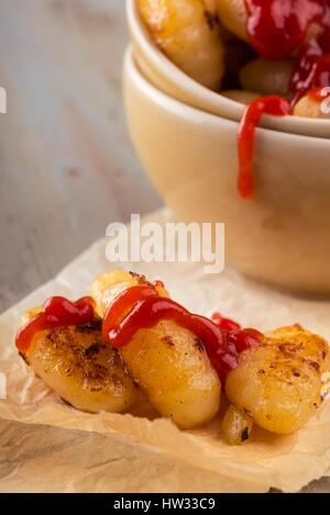 Photo verticale avec plusieurs morceau de gnocchis faits maison sur le morceau de papier en face de bols. Portion de pâtes est placé sur vintage wooden board avec wor Banque D'Images