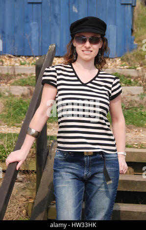 Belle brune jeune femme en jeans et t-shirt à rayures portant une casquette Banque D'Images