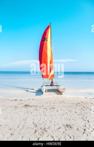 Un voilier repose sur une plage de sable blanc des Caraïbes avec un beau bleu turquoise de la mer en arrière-plan. La mer est encore. Places gratuites pour une belle mise en page. Banque D'Images