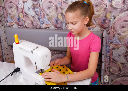 Fille apprend à coudre sur une machine à coudre électrique Banque D'Images