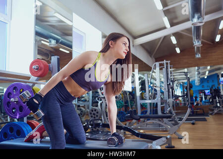 Jeune fille sportive avec haltères en mains en faisant des exercices spo Banque D'Images