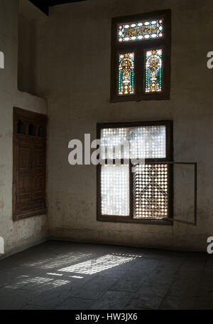 Old abandoned dark endommagé chambre sale avec deux cassé des fenêtres ornées de bois couverts par la grille en bois entrelacé (mashrabiya) Banque D'Images