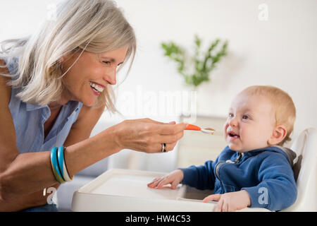 Smiling Caucasian grand-mère petit-fils à nourrir bébé Chaise haute Banque D'Images