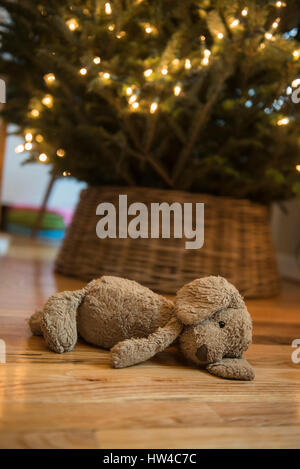 Ours en peluche portant sur le plancher près de l'arbre de Noël Banque D'Images