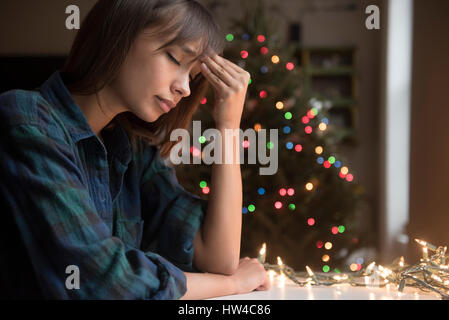 Mixed Race woman avec maux near Christmas Tree Banque D'Images