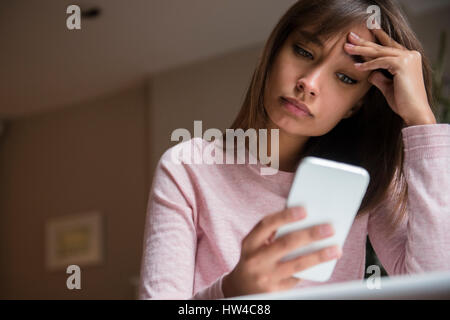 Frustrés Mixed Race woman texting on cell phone Banque D'Images