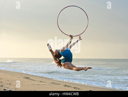 Young gymnast jumping with hoop on beach Banque D'Images