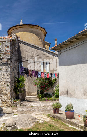 Maisons en pierre et stuc, une église, et de blanchisserie suspendu entre deux bâtiments dans la cité médiévale et italienne ville croate de Buzet. Banque D'Images