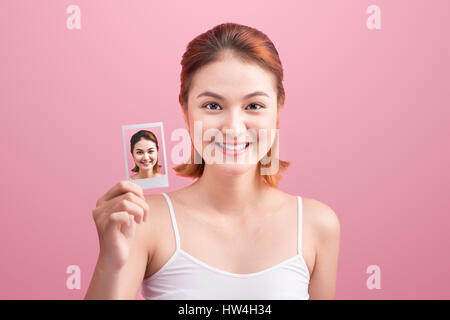 Young Asian woman holding her photo Polaroid sur fond rose. Banque D'Images