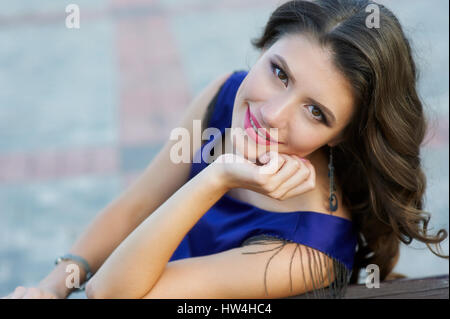 Belle brown-haired woman sitting on bench in park Banque D'Images