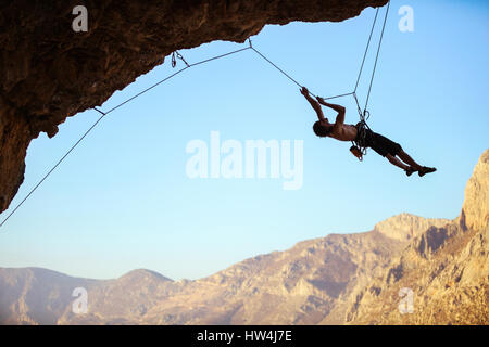 Rock climber tirant lui-même jusqu'à l'aide de corde pour atteindre Falaise dégaines sur afin de les supprimer Banque D'Images