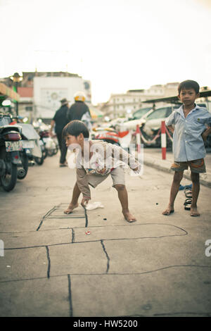 Deux enfants jouent à la marelle Khmer et s'amuser dans une rue de Phnom Penh, Cambodge. Banque D'Images