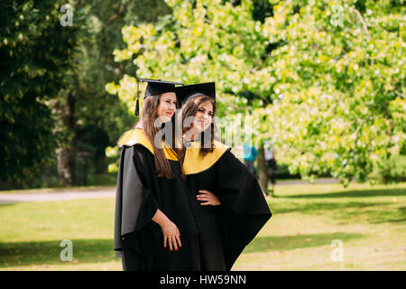 Riga, Lettonie - 1 juillet 2016 : Deux jeunes femmes diplômées de l'Université de Lettonie habillé en robe de chambre et les diplômés universitaires Square caps qui pose pour la photo Banque D'Images