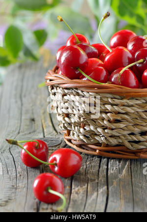 Les cerises mûres dans un panier sur la table en bois Banque D'Images