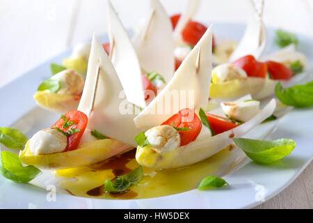 Les feuilles d'endives farcies de tomates cerise et billes de mozzarella, habillé avec de l'huile d'olive et vinaigre balsamique Banque D'Images