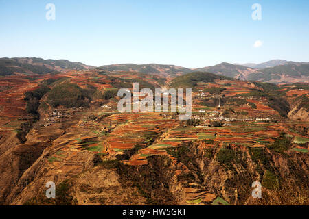 Vue panoramique de l'agriculture chinoise paysage du village entouré de montagnes et collines de couleur rouge dans la matinée. Banque D'Images