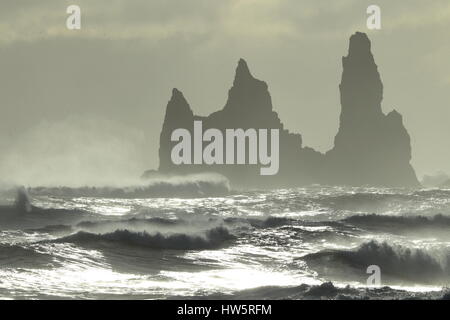 Les piles de la mer de Reynisdrangar, Islande vagues se brisant sur Renisfjara plage en face de l'basaltiques de Reynisdrangar, le sud de l'Islande Banque D'Images