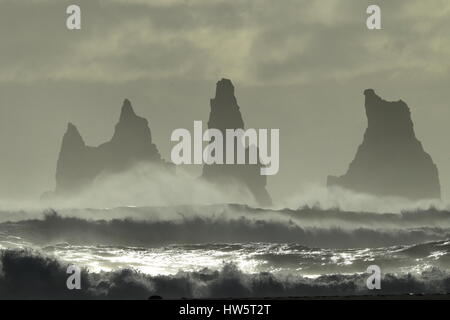 Les piles de la mer de Reynisdrangar, Islande vagues se brisant sur Renisfjara plage en face de l'basaltiques de Reynisdrangar, le sud de l'Islande Banque D'Images