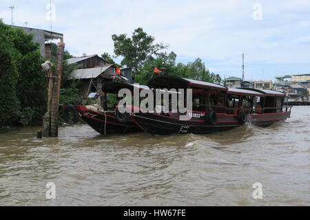 Mékong en Indochine, il vous suffit de bateau en bois sur la rivière sale avec des maisons sur des piliers colorés voile unique. Banque D'Images