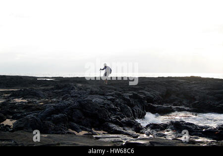 Une femelle solo traveler utilise les bâtons de marche pour parcourir la lave pahoehoe dans Puerto Egas sur l'île de Santiago dans les Galapagos, Equateur Banque D'Images