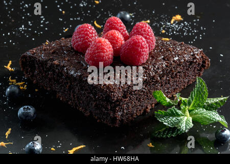 Gâteau au chocolat avec des framboises, bleuets, le zeste d'orange et pipermint Banque D'Images