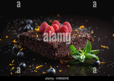 Gâteau au chocolat avec des framboises, bleuets, le zeste d'orange et pipermint Banque D'Images