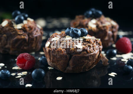 Muffins au chocolat avec des framboises, des bluesberries et d'avoine. Banque D'Images