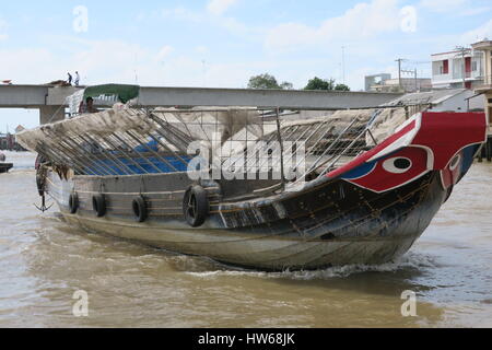 Mékong en Indochine, il vous suffit de bateau en bois sur la rivière sale avec des maisons sur des piliers colorés voile unique. Banque D'Images