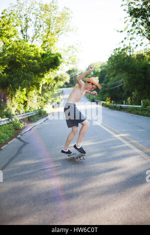 Boy skateboarding en bas de la route Banque D'Images