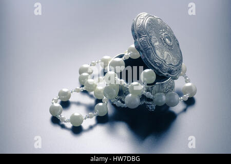 Photo d'une boîte de bijoux en argent avec perles blanches tourné avec projecteurs et fond noir Banque D'Images