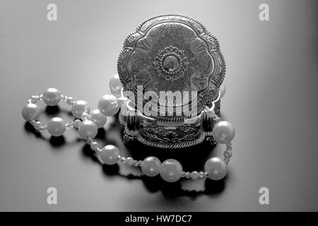 Photo d'une boîte de bijoux en argent avec perles blanches tourné avec projecteurs et fond noir Banque D'Images