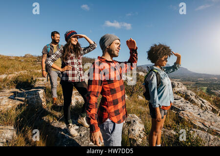 Groupe d'amis à profiter de la vue de sommet. Les jeunes, hommes et femmes, l'article sur le pic de production et à la recherche à une vue. Banque D'Images