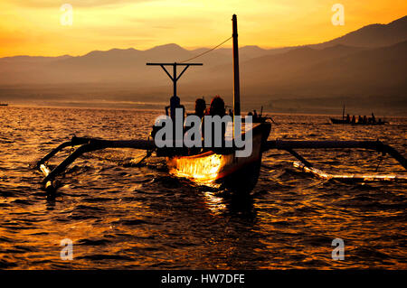 Le soleil qui illumine un outrigger canoe au large de Lovina, à Bali en Indonésie. Banque D'Images