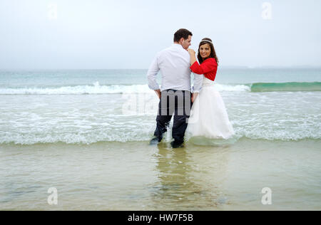 Couple marié jouant dans l'eau de mer Banque D'Images