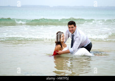 Couple marié jouant dans l'eau de mer Banque D'Images