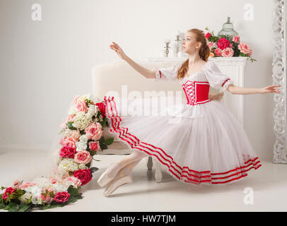 Ballerine mignon en costume de scène à côté de bouquets de fleurs de printemps. Robe rétro. Banque D'Images