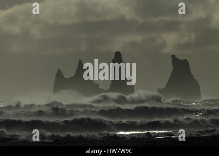 Les piles de la mer de Reynisdrangar, Islande vagues se brisant sur Renisfjara plage en face de l'basaltiques de Reynisdrangar, le sud de l'Islande Banque D'Images