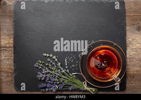 Dans un verre de thé à la lavande, coupe du bouquet de lavande fraîche sur un fond en ardoise noire (vue de dessus) Banque D'Images