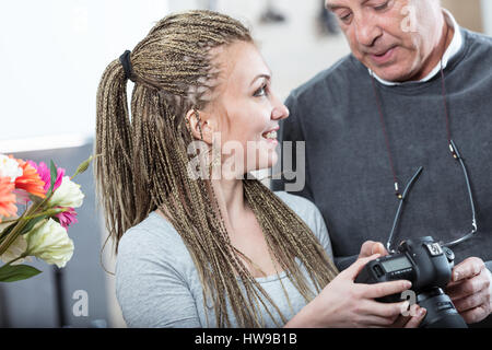 Jeune femme aux tresses micro hairstyle et man chandail gris debout avec photo caméra comme si regarder des photos, man man, fermer Banque D'Images