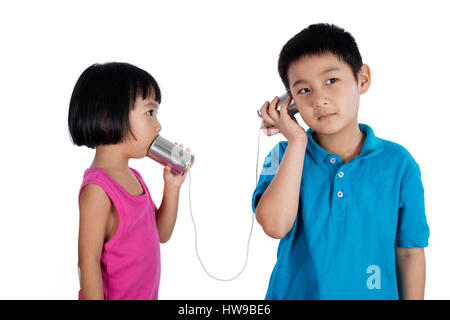 Chinois asiatique Kid jouer avec Tin Can Téléphone isolé sur fond blanc Banque D'Images