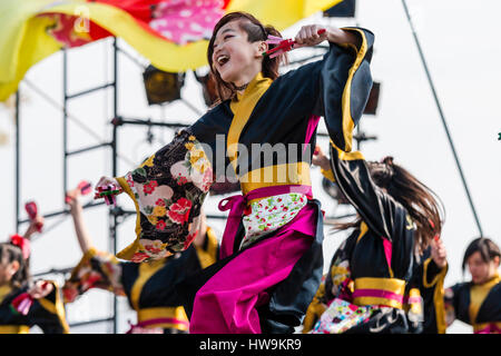 Danse Yosakoi Festival. Enfant souriant, girl, danse en noir et jaune, veste yukata holding naruko, tout en dansant avec les autres. Low angle view. Banque D'Images